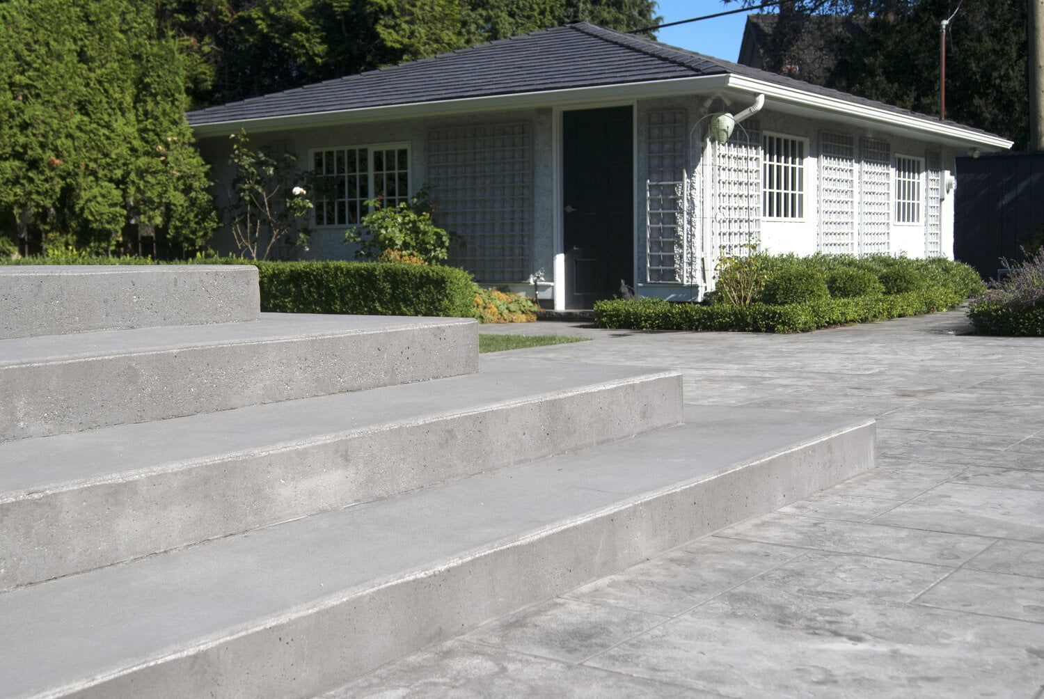 Wide architectural concrete steps leading to natural stone tile pool terrace at vancouver residence