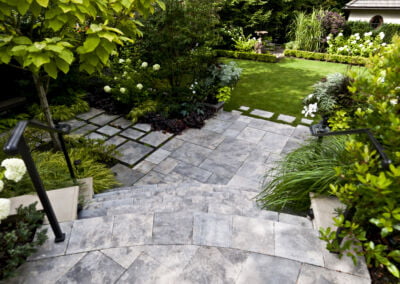 Stone stairs to stone patio and lawn in vancouver garden with lush planting