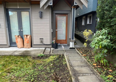 East Vancouver front entry before landscape redesign — sparse lawn, minimal planting, and limited street privacy on a corner lot.